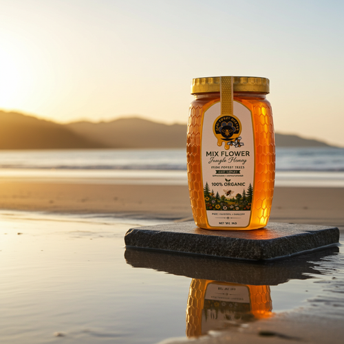 A jar of Mix Flower Raw Unfiltered Honey stands on a dark stone slab at the edge of a beach during sunset. The honey is golden amber, and the background shows a calm shoreline with soft warm light.